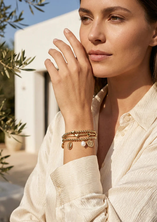 Gold triple layer bead and bar elasticated bracelet with pearl and shell charms